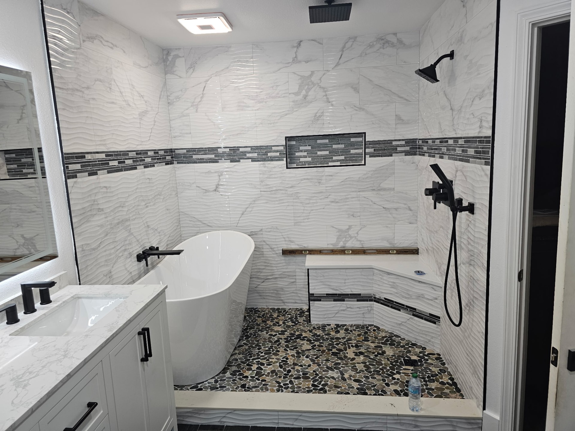 Luxury stone bathroom with freestanding tub and coastal light